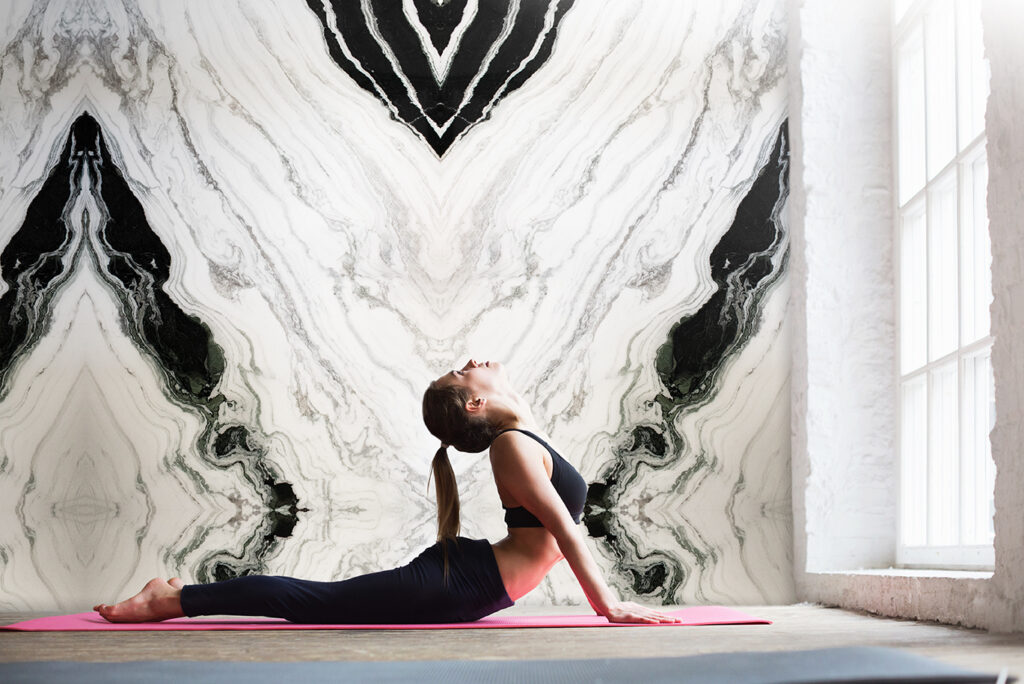 women in yoga pose in front of panda white marble wall